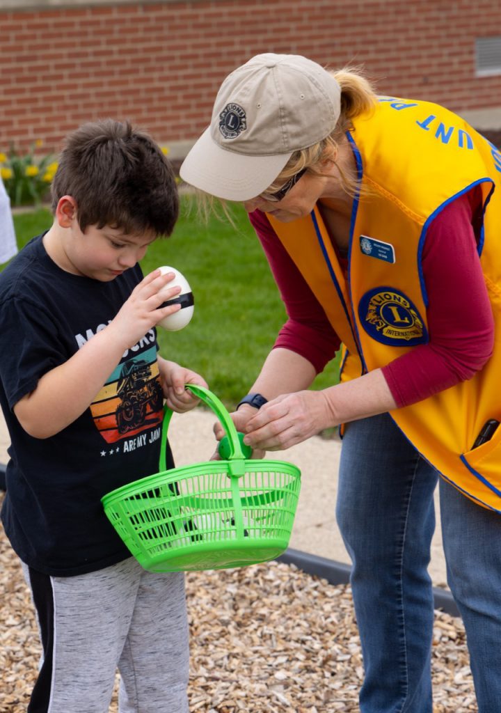 A Mount Prospect Lions Club member helps a boy count his eggs.